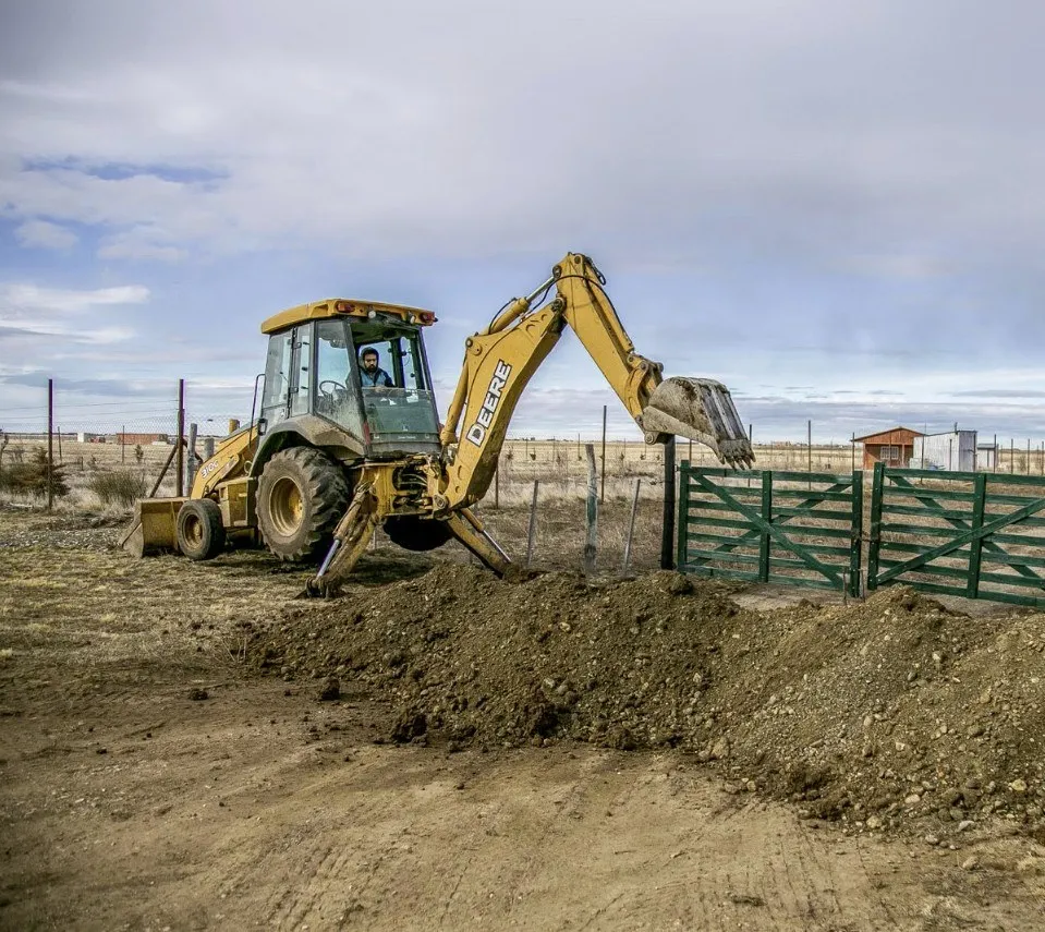 A backhoe excavator digging a trench on a rural property — illustrative stock photo, not an actual Pahrump job site